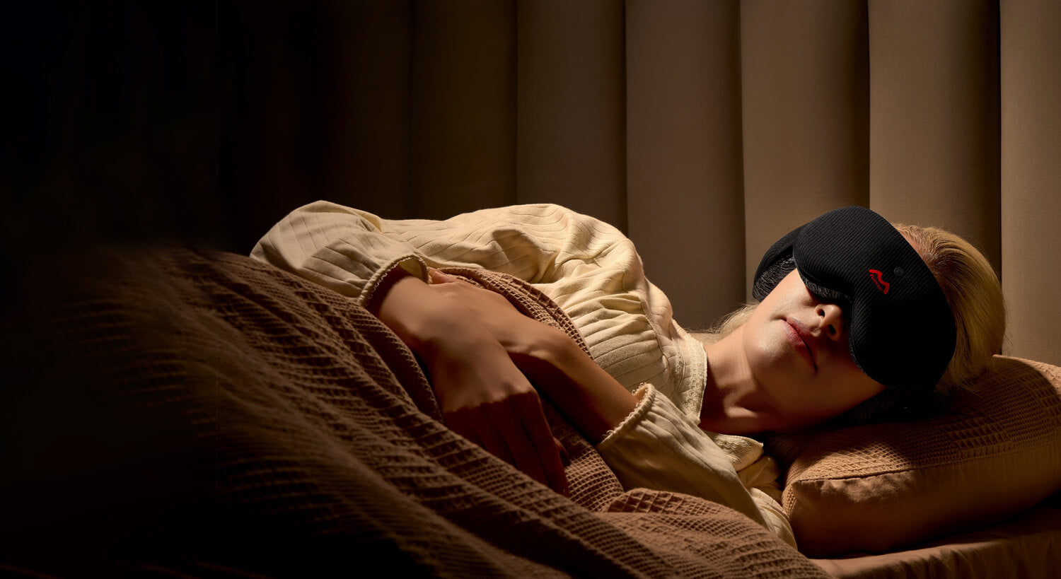 Fismool sleep mask worn by a woman in a dimly lit bedroom, providing full light blocking for a restful night’s sleep.