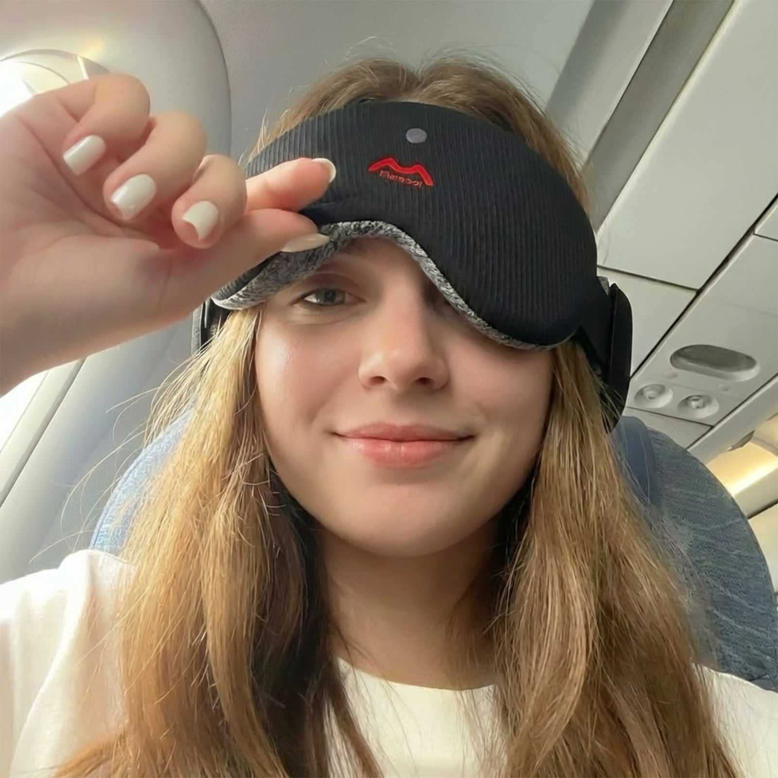 Fismool sound sleep mask black worn on airplane for travel, featuring deep eye cups and Bluetooth audio for comfortable in-flight sleep
