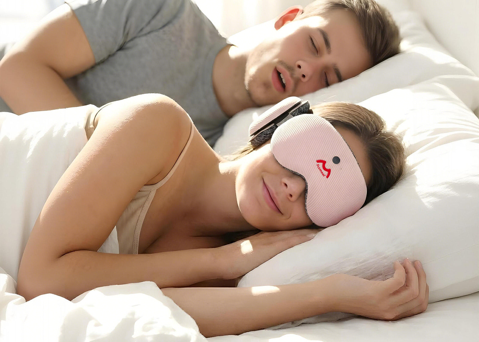 Two people lying in bed, one wearing a Fismool sound sleep mask pink to block noise while sleeping